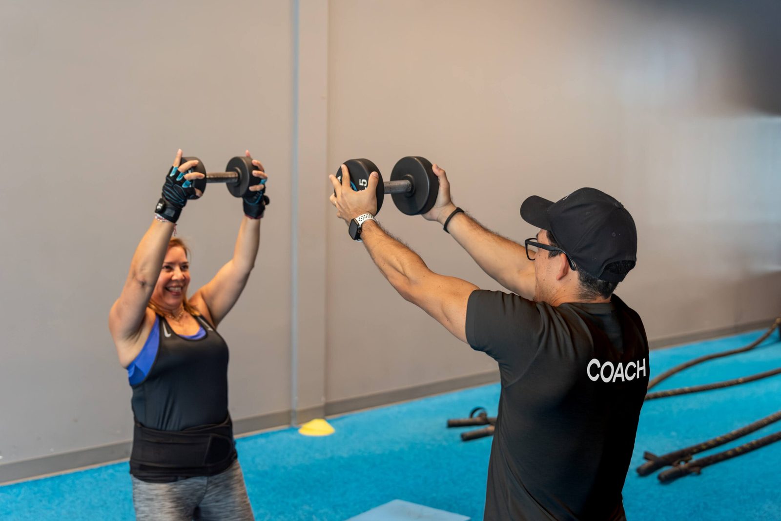 Coach and member working out gym class SWEAT440