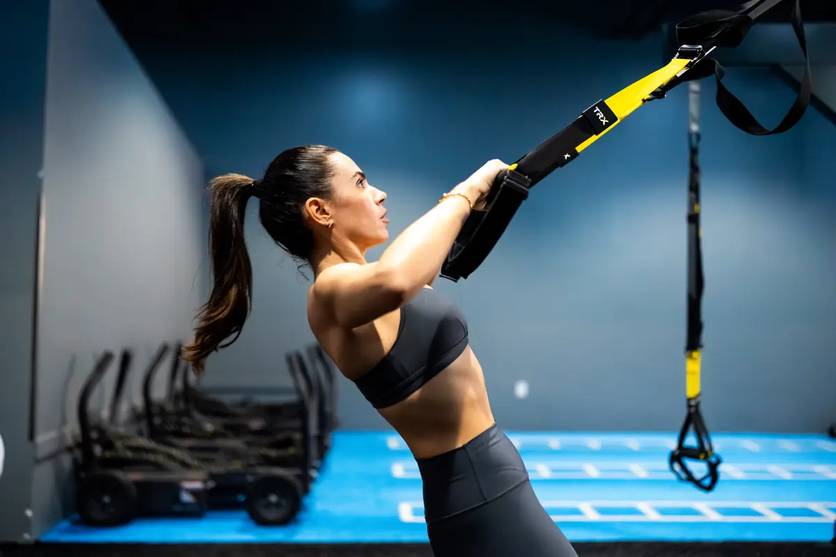 Woman doing a TRX row during a SWEAT440 strength workout