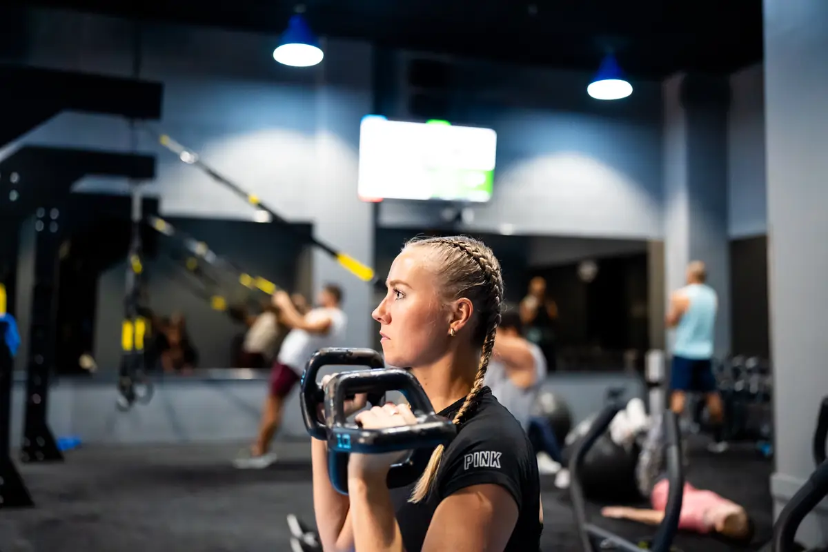 Woman holding a dumbbell during a free weight exercise at SWEAT440
