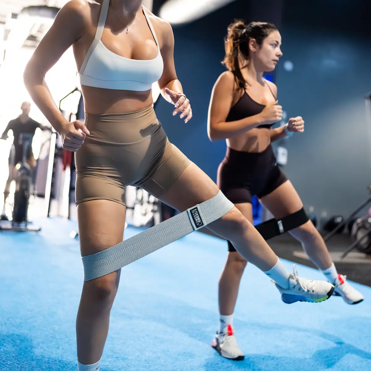 Two women doing lateral walks with resistance bands around their legs