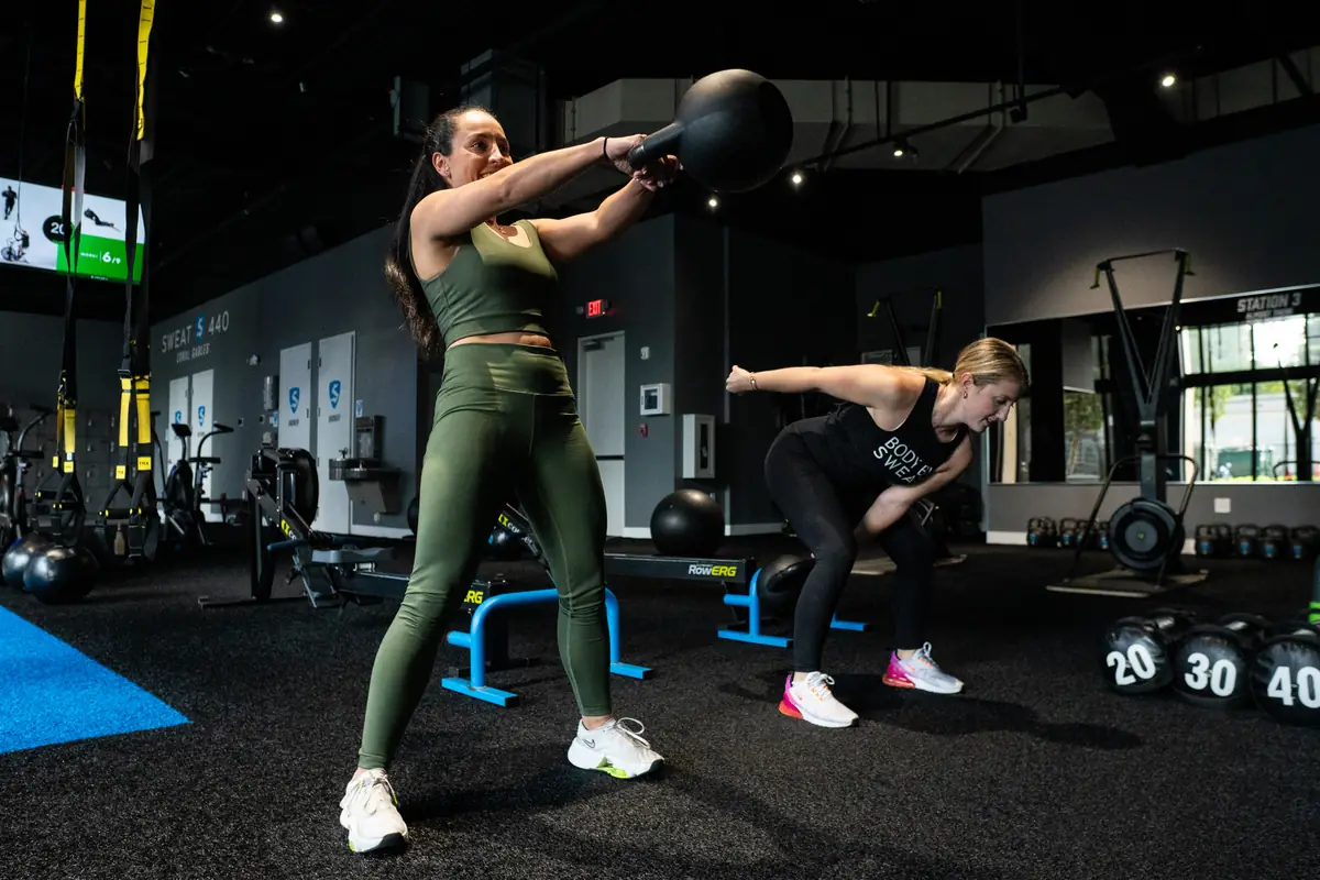 Two women training with kettlebells during a full body workout