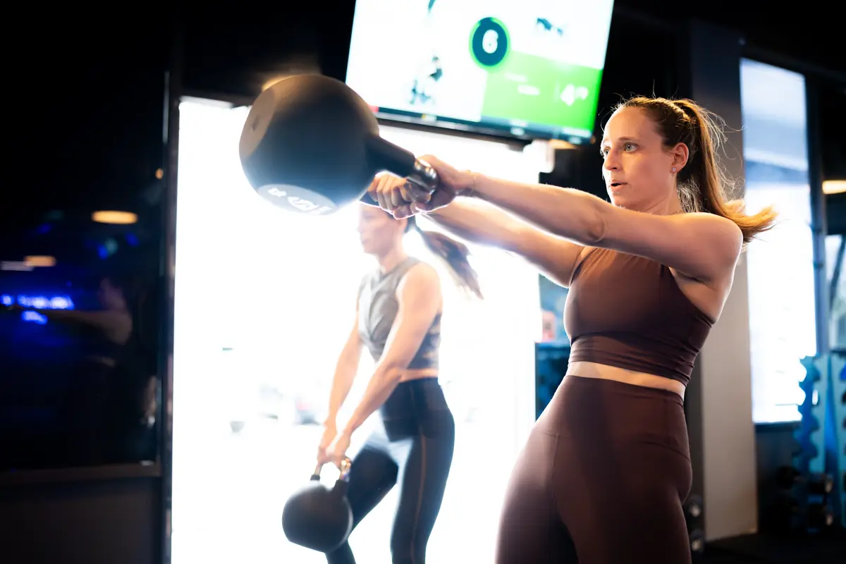 Women performing kettlebell swings in a SWEAT440 class