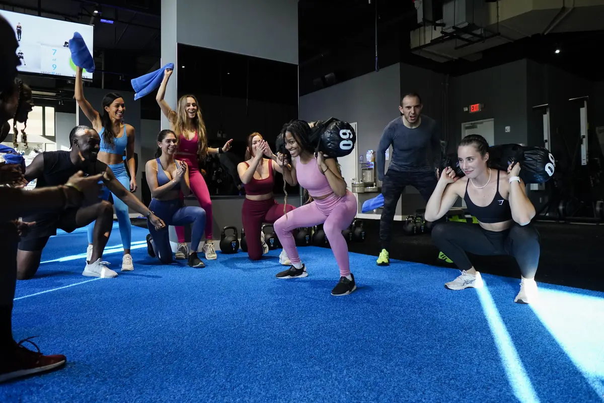 Group of SWEAT440 members doing sandbag squats together