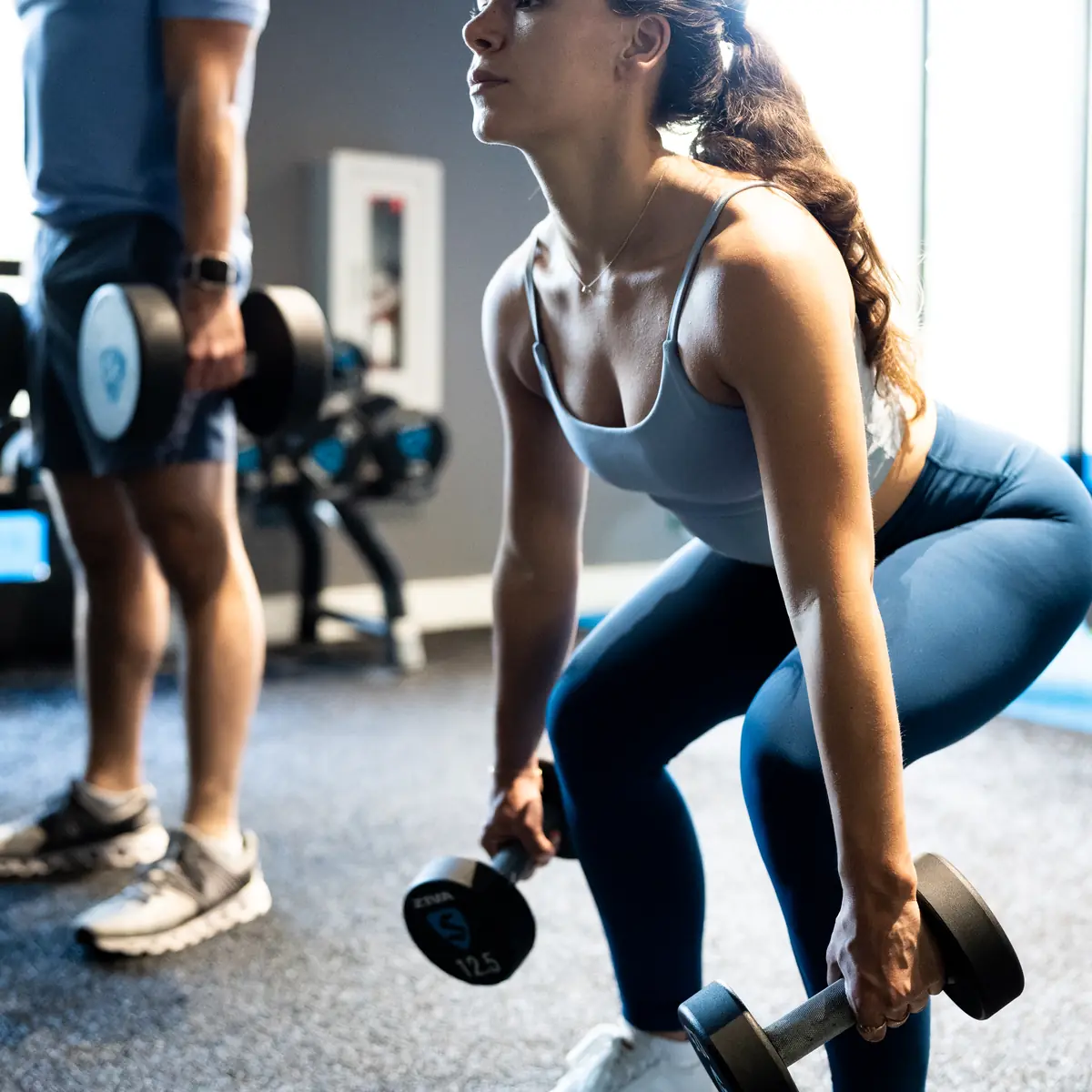 Woman doing a dumbbell Romanian deadlift during a SWEAT440 strength class
