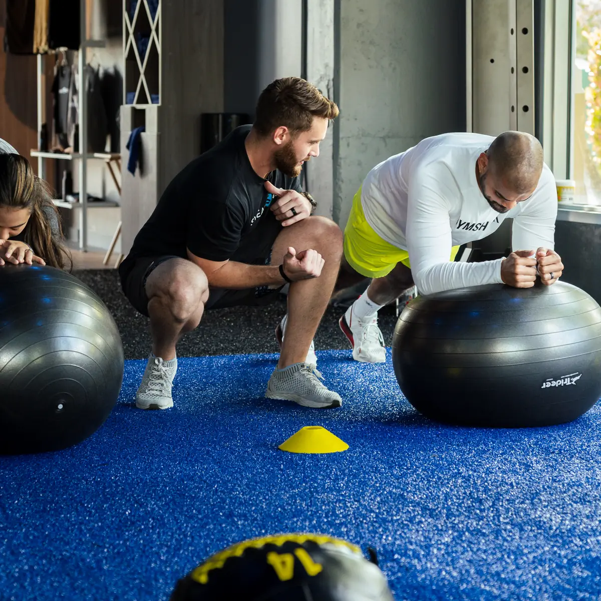 SWEAT440 coach guiding a member through a stability ball core exercise