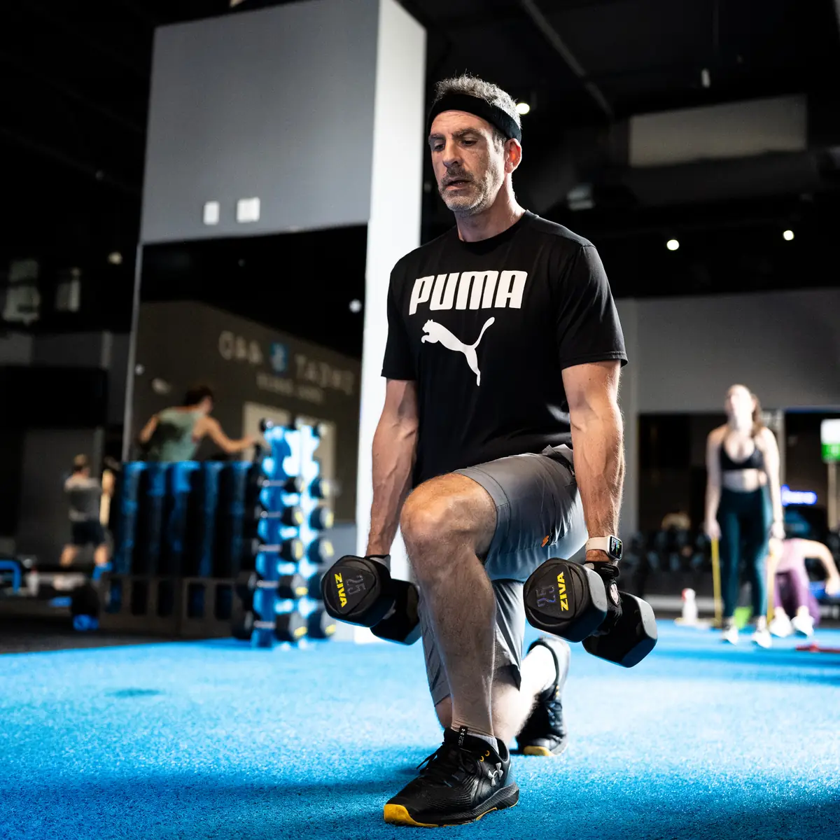Man doing a dumbbell lunge during a SWEAT440 class