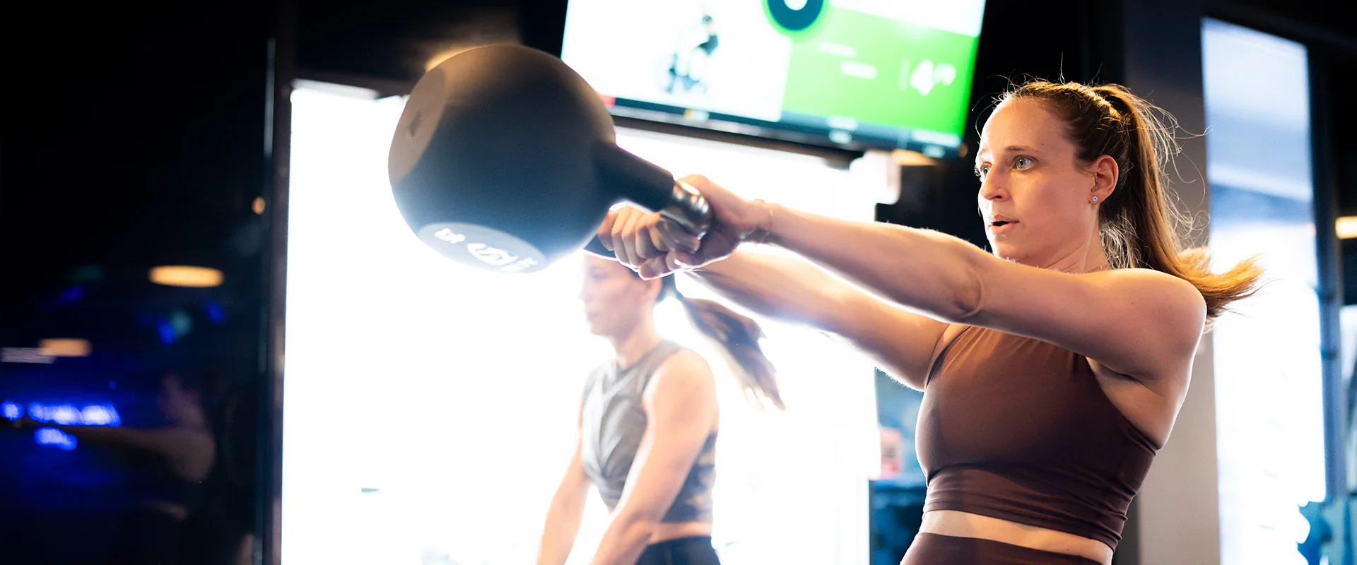 SWEAT440 member doing a kettlebell swing during a group class