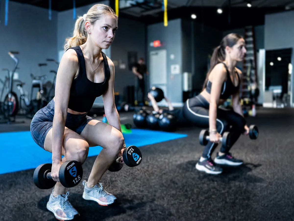 SWEAT440 members doing dumbbell squats for lower body strength training