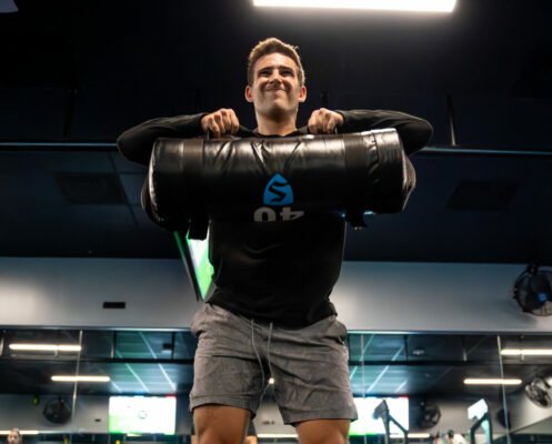 SWEAT440 Gym class member working out sand bag